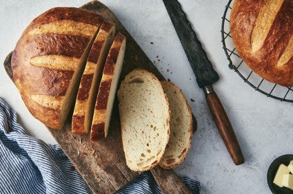 Round loaf of sourdough bread, dark mahogany crust, sliced on a cutting board.