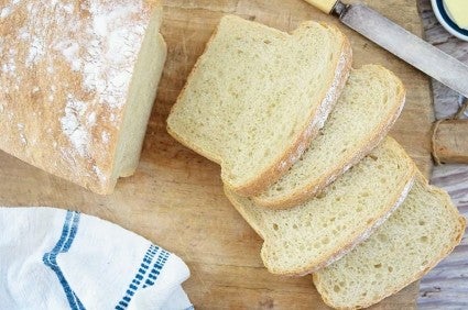 Loaf of sourdough sandwich bread sliced on a cutting board.